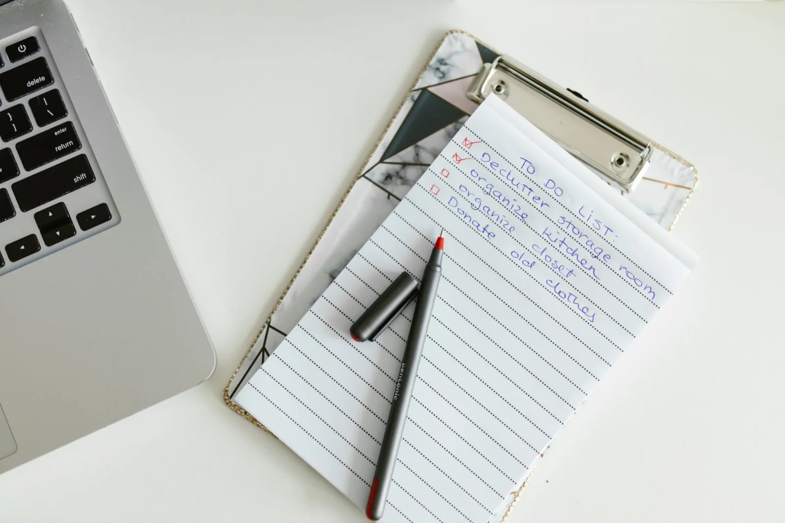 Laptop neben einer gedruckten Prüfliste mit handschriftlichen Markierungen auf einem Schreibtisch